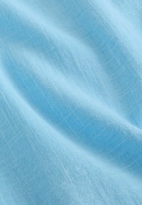 Tissu bleu clair avec une texture douce, présentant un motif en grille subtil et une légère brillance. Le matériau semble léger et aérien.