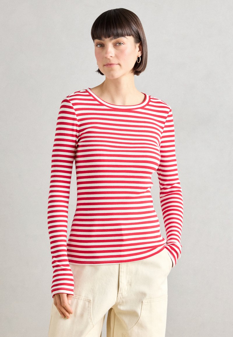 Red and white striped long-sleeve t-shirt made of ribbed fabric with a round neckline, featuring thumbholes at the sleeve cuffs.