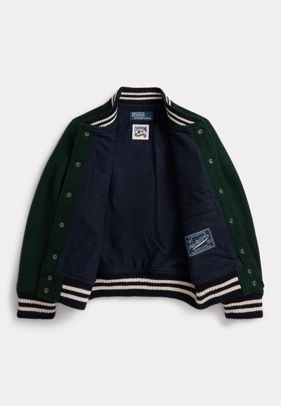 Zaļš vilnas kardigans ar tumši zilu iekšējo oderi, ivoāra un tumši zilu svītrojumu ribotām piedurknēm un apakšmalu, ar spiedpogām, iekļaujot zīmola etiķetes iekšpusē.