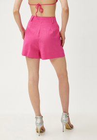 Roze linnen shorts met een hoge taille en een relaxte pasvorm. Bevat riemlussen en zijzakken. Gecombineerd met geregen iriserende hoge hakken.