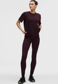 Burgundia spordi komplekt, mis sisaldab avarat T-särki ja istuvaid retuuse. Pehme, veniv kangas, minimalistlik disain ning ilma nähtavate mustrite või logodeta.