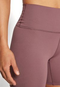 Vysoké cyklistické šortky v barvě malinové, vyrobené z pružného materiálu. Mají ploché švy a hladkou texturu pro pohodlí při nošení.