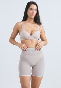 Sutien bej fără cusături, cu bretele late și pantaloni scurți modelatori cu talie înaltă, asortați. Textură netedă și cusături minime. Potrivit pentru a fi purtat în straturi.
