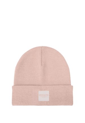 Junger Mann mit leichtem Schnurrbart, der eine rosa gestrickte Mütze und ein schwarzes kariertes Hemd trägt, schaut leicht zur Seite mit einem leichten Lächeln.