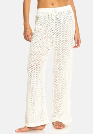 Pantalons blancs légers en tissu tissé avec une coupe ample, présentant une taille à cordon de serrage et un motif texturé ouvert.