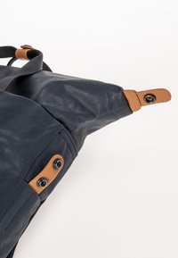 Borsa in pelle blu navy con finitura testurizzata, dotata di dettagli marrone chiaro e chiusure a scatto prominenti sui lati per una forma regolabile.