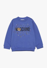 Blå barntröja med "Moschino"-text, ett teddy-björnsansikte och färgglada musiknoter och stjärnor på framsidan.