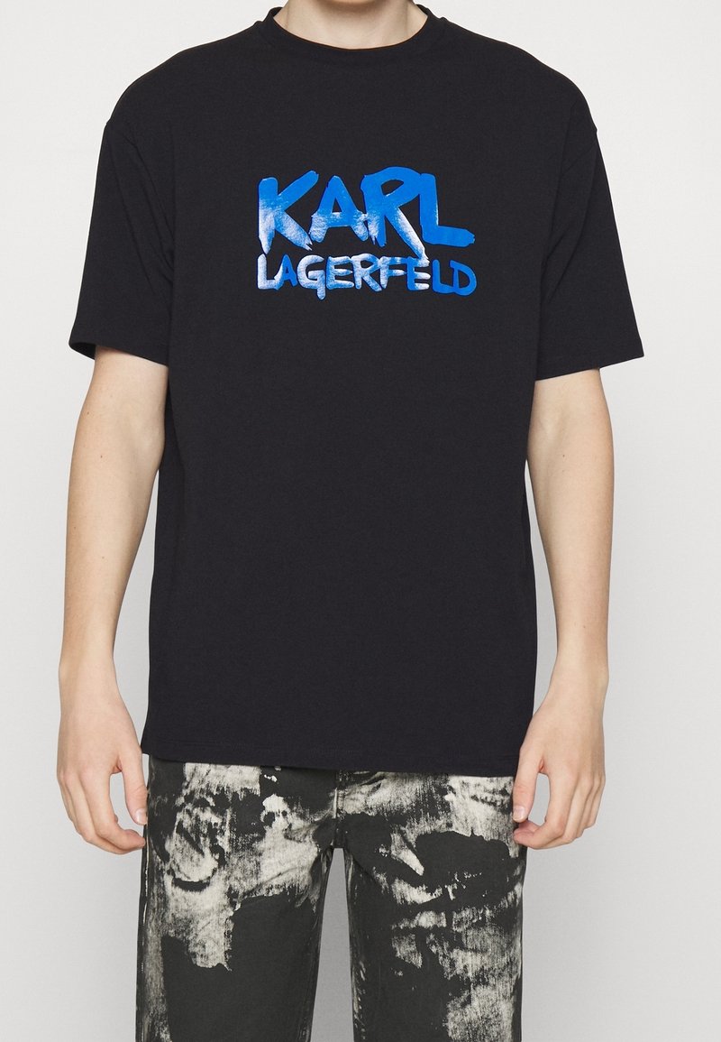 Schwarzes T-Shirt mit auffälligem blauen "KARL LAGERFELD" Schriftzug auf der Brust. Das Material wirkt weich, mit einem klassischen Schnitt und entspanntem Sitz.
