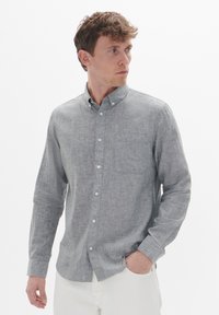 Grijze button-up shirt met lange mouwen, een borstzak en een gestructureerde stof. Heeft witte knopen en een kraag.