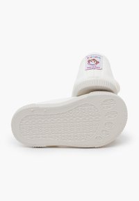 Witte kinderschoenen met een rubberen zool, gestructureerd patroon en een apenlabel op de hiel. Gemaakt in Spanje.