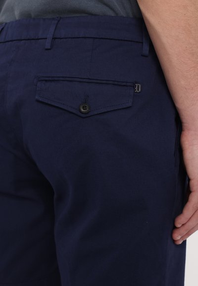 Pantaloni din bumbac bleumarin, cu un buzunar la spate cu un sistem de închidere cu buton și un detaliu de clapetă a buzunarului în contrast. Textură netedă, croială ajustată.