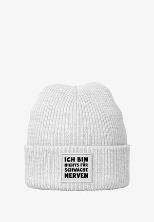 Weiße gestrickte Mütze mit gerippter Textur und umgeschlagenem Bündchen, auf dem ein rechteckiges Schild mit der Aufschrift "ICH BIN NICHTS FÜR SCHWACHE NERVEN" in Schwarz angebracht ist.