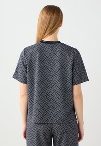 Krótki rękaw top w granatowym kolorze z geometrycznym wzorem diamentów w białym i niebieskim. Posiada okrągły dekolt i luźny krój.