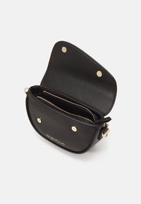 Borsa a tracolla in pelle nera con hardware in tonalità oro, due scomparti con zip e chiusura a pressione magnetica. Nome del marchio impressa sul davanti.