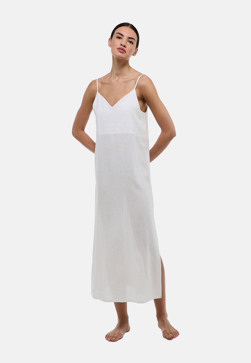 Robe maxi blanche avec un décolleté en V, des bretelles fines et une coupe ample. Fabriquée en tissu léger, elle présente une texture semi-transparente et des fentes sur les côtés.