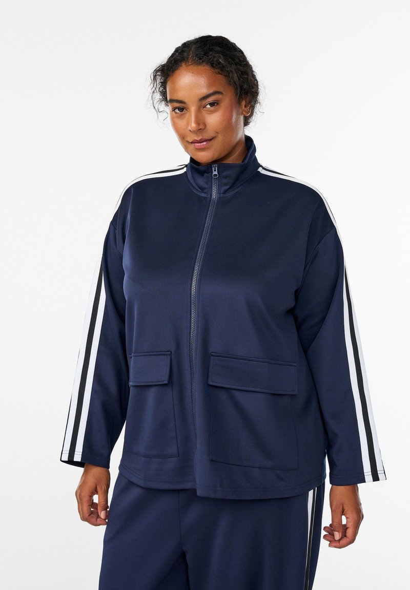 Marinefarbener Reißverschlussjacke mit hohem Kragen, zwei Fronttaschen und weißen Streifen an den Ärmeln. Hergestellt aus glattem, leichtem Stoff.