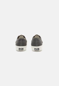 Svarte lerrets sneakers med et teksturert mønster og hvite gummisåler. Har en liten "Off the Wall" logo på hælen. Rund tådesign.