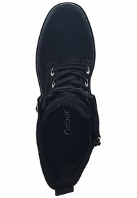 Stivaletto nero con tomaia in suede, punta rotonda e design con lacci; include una zip laterale e una soletta con marchio.