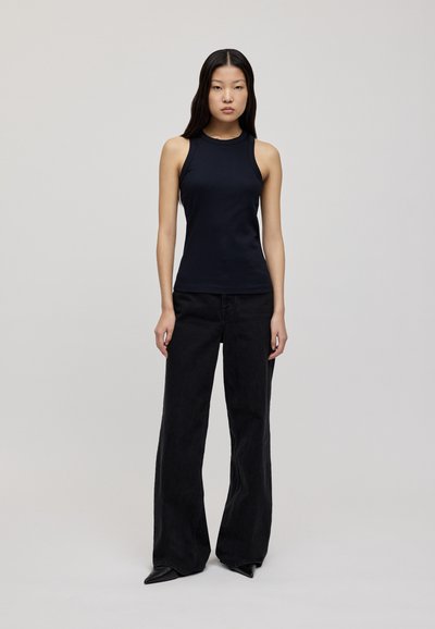Dark sleeveless top paired with high-waisted black flared jeans. Smooth fabric with a fitted design, simple neckline, and tapered pant legs.