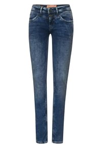 Hubené džíny vyrobené z denimu, s tmavě modrým odstínem, dvěma knoflíky v pase a pěti kapsami se diskrétními švy.