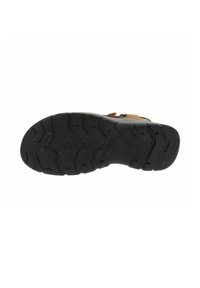 Suela de goma negra con un patrón de banda texturizado, diseñado para ofrecer agarre. Parte superior de color marrón claro con una malla transpirable, asegurada con correas ajustables.