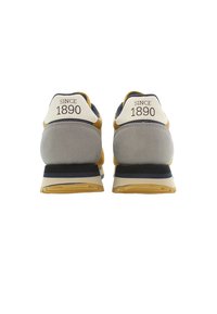 Harmaa ja laivansiniset urheilukengät, joissa on kumipohjat, tamman accentti ja "SINCE 1890" -painatus kantaosassa. Sileä pinta, moderni muotoilu.