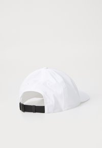 Hvit baseballcaps laget av stoff, med skrått visir, justerbar svart stropp bak, og søm detaljer på kronen.