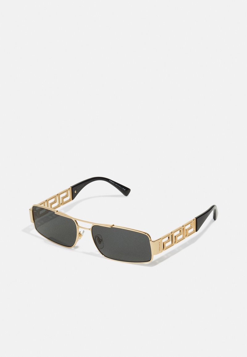 Ochelari de soare din metal aurit, cu lentile dreptunghiulare întunecate și modele geometrice intricate pe brațe. Accente negre pe părțile pentru urechi.