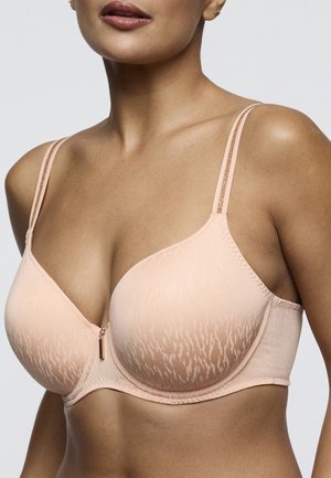 Vrouw met een lichtroze beha met patroon en dunne, glinsterende dubbele bandjes en beugelondersteuning, afgebeeld van nek tot midden torso.