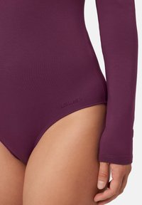 Body a maniche lunghe in tessuto viola intenso, con una texture liscia e branding ridotto sul lato inferiore.