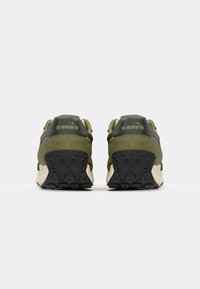 Green suede and black leather sneakers with a textured rubber sole. Back features a logo and dual-tone design for added detail.