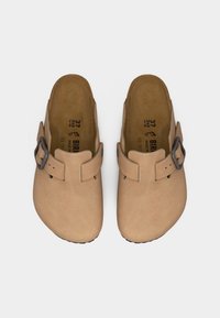 Ζευγάρι μπεζ κλειστά παπούτσια τύπου σφήνας με ρυθμιζόμενα μαύρα λουράκια με αγκράφα και διαμορφωμένες εσωτερικές σόλες, μέγεθος 37, τοποθετημένα σε λευκό φόντο.