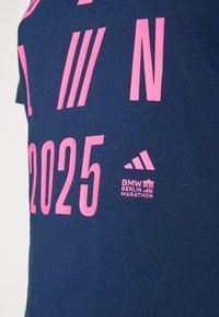 Marineblå t-shirt med pink grafiktryk, der viser "N", "2025" og Adidas-logoet med teksten "BMW BERLIN MARATHON". 100% bomuldsmateriale.