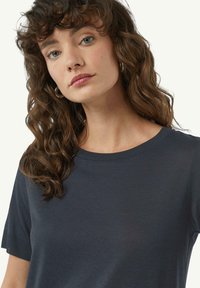 Granatowa koszulka z krótkim rękawem z okrągłym dekoltem, wykonana z miękkiego materiału; ma luźny krój i subtelne prążkowane akcenty u dołu.