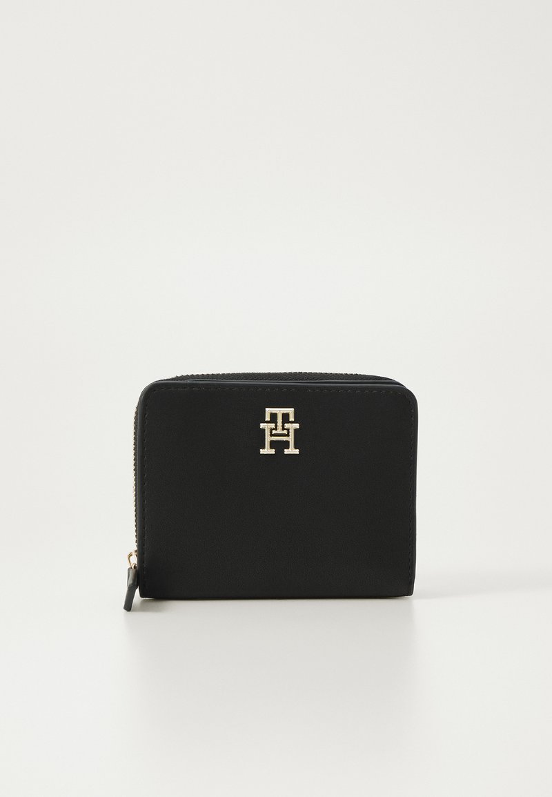 Black zippered wallet made of smooth leather. Features a gold logo accent on the front. Compact rectangular shape, minimalistic design.