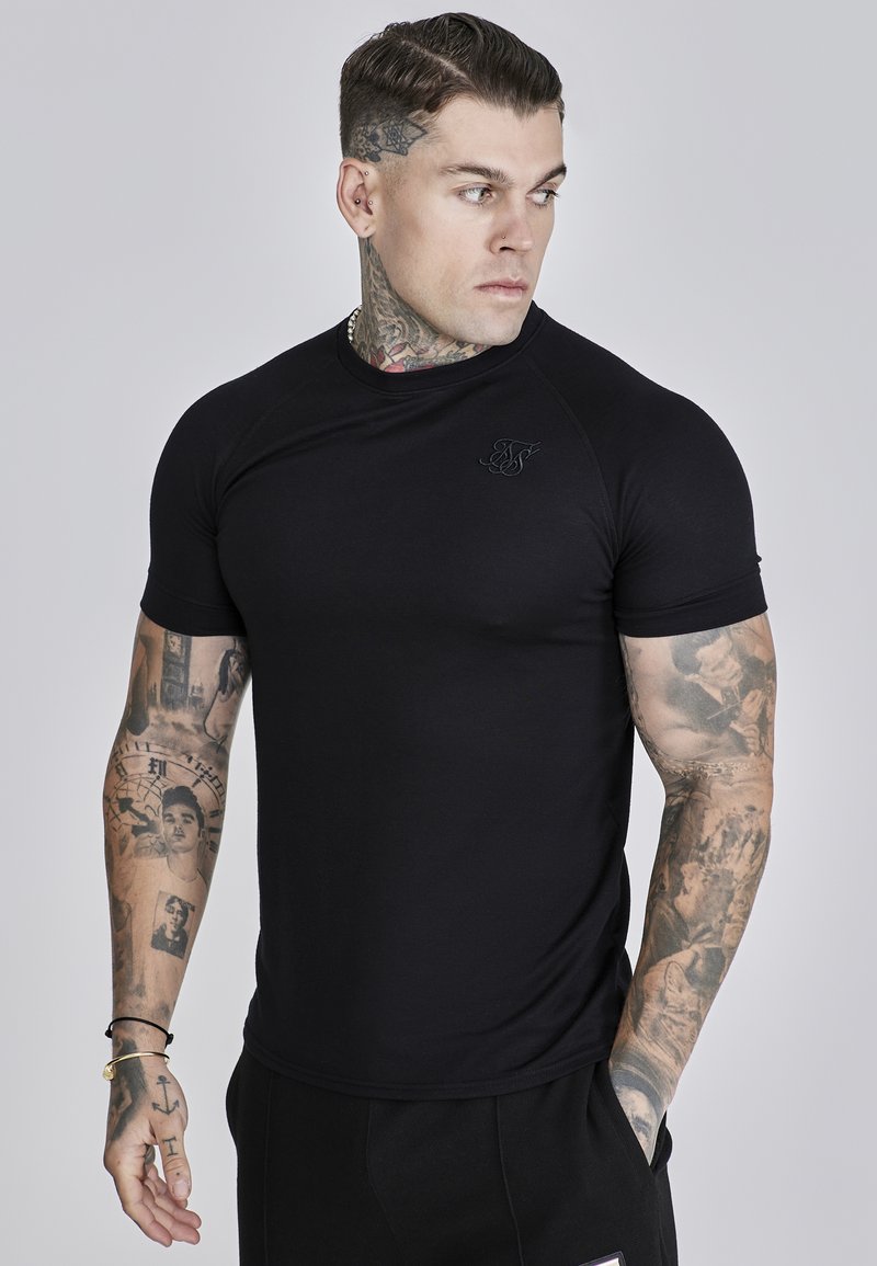 Crna kratka sportska majica s prilagođenim dizajnom, glatkom teksturom i izvezenim logom na prsima. Casual stil, u kombinaciji s crnim hlačama.