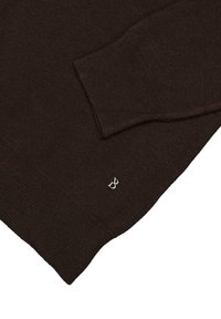 Brązowy sweter z miękkiego materiału, z prążkowanymi mankietami i dolnym brzegiem. Małe srebrne logo znajduje się blisko dolnego brzegu z przodu.