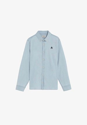 Camisa de manga larga azul claro con botones en la parte delantera, cuello abotonado y pequeño emblema de calavera negra en el lado izquierdo del pecho.