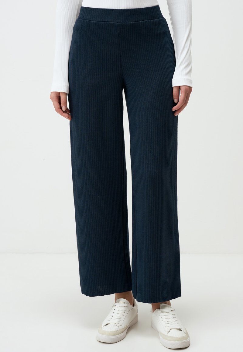 Navy brede broek gemaakt van ribbelstof, met een hoge tailleband en een losse pasvorm, gecombineerd met witte sneakers.