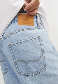 Ljusblå denimjeans med en läderlogotyp, dekorativ sömnad på bakfickorna och en klassisk femficksdesign.