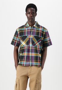 Short-sleeve checkered shirt featuring multicolored plaid patterns in purple, black, yellow, and teal; two chest pockets; button-down front.