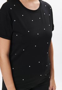 T-shirt nera a maniche corte realizzata in cotone, caratterizzata da paillette di argento sparse sul davanti, scollatura rotonda e vestibilità comoda.