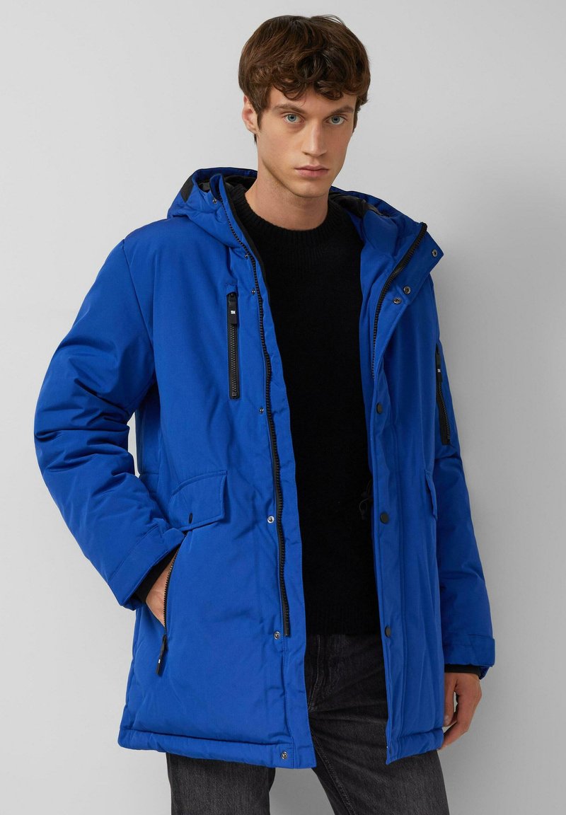 Blauer gepolsterter Parkajacke mit einem Reißverschluss und Knopfverschluss, ausgestattet mit einer Kapuze, zwei mit Reißverschluss versehenen Taschen und einer strukturierten Oberfläche.