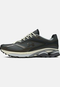 Chaussure de course athlétique noire et grise avec lacets blancs, tige en mesh texturé, semelle amortissante et logo Under Armour sur le côté.