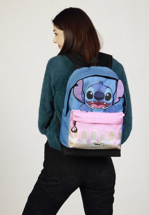 Mochila con una base azul y un estampado de personajes de dibujos animados, diseño de gotas rosas en el bolsillo frontal y asas negras.