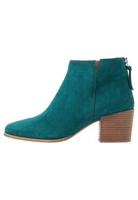 Turkoosinsininen mokkanahkainen nilkkureppu, jossa on teräväkärkinen varvas, kohokuvioitu sivusauma ja pinoitettu puukorko. Varustettu koristeellisella vetoketjulla ja hapsuilla.