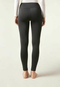 Svarta leggings tillverkade av ett glatt, elastiskt material. Hög midja med sömlös finish och knälång längd.