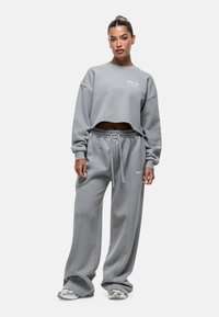 Grijze cropped sweatshirt en bijpassende high-waisted sweatpants, beide van zacht materiaal, met logo-detail en elastische tailleband.