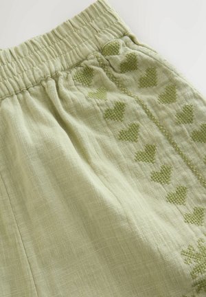 Helle grüne Leinen-Shorts mit elastischem Bund und aufgestickten Herzmustern in einem dunkleren Grün entlang der Seitennähte.