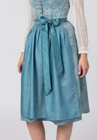 Ein blaues gemustertes Kleid aus strukturiertem Stoff, mit einem satinierten Taillengürtel, der zu einer Schleife gebunden ist. Die Ärmel sind aus durchsichtiger Spitze mit einem knöpfbaren Oberteil.